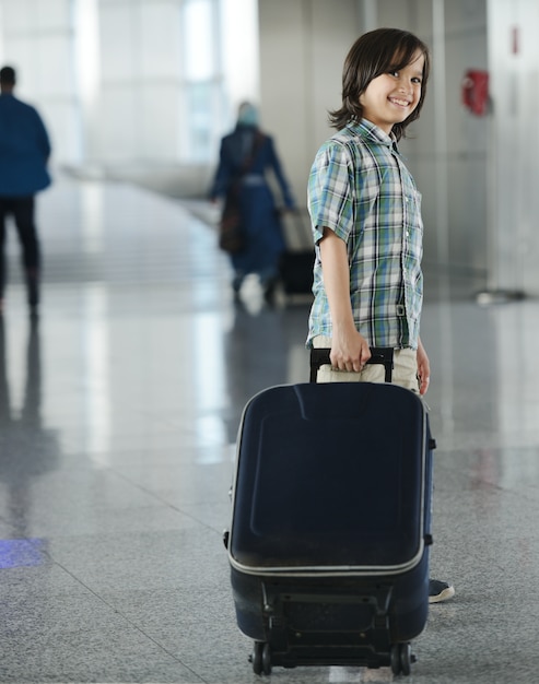 Niño lindo con el bolso en el viaje del aeropuerto