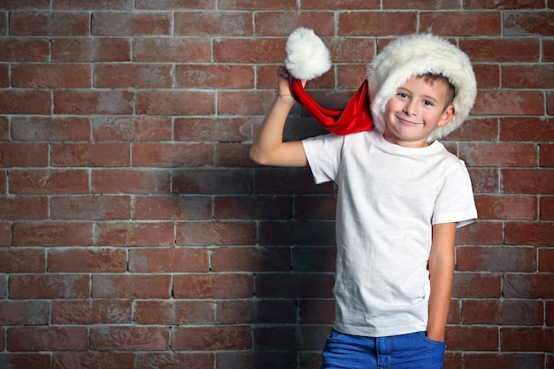 Niño lindo con caja de regalo en la superficie de la pared de ladrillo.