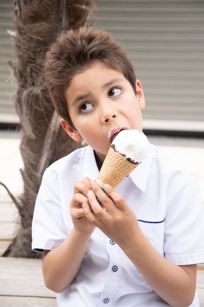 Foto el niño lindo con la cara sucia come helado el niño disfruta del postre