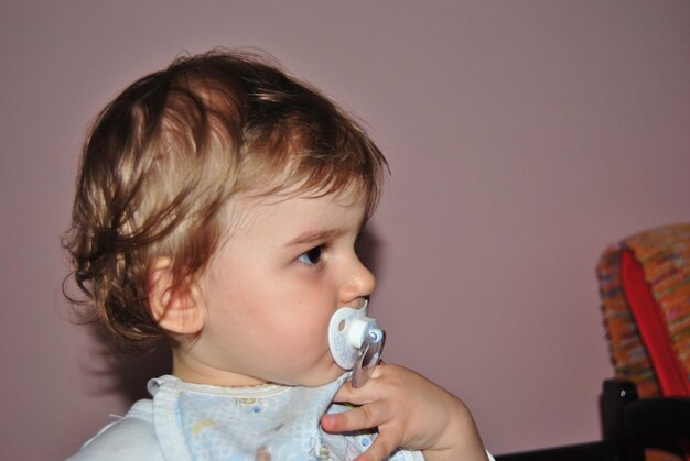 Un niño lindo chupando un chupete en casa.