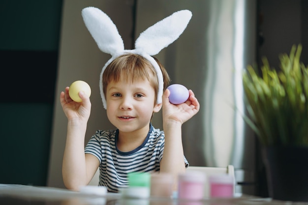 Un niño lindo coloreando huevos para la Pascua.