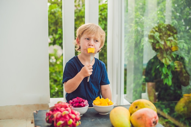 Foto niño lindo comiendo mango en la terraza