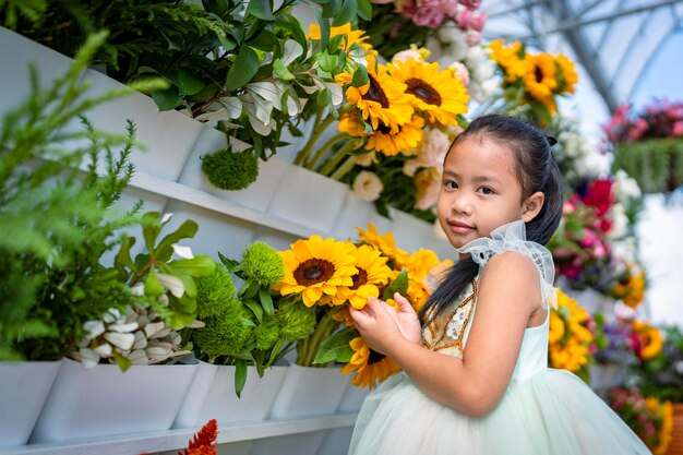 Foto niño lindo contra un ramo de girasoles en flor mirando hacia otro lado