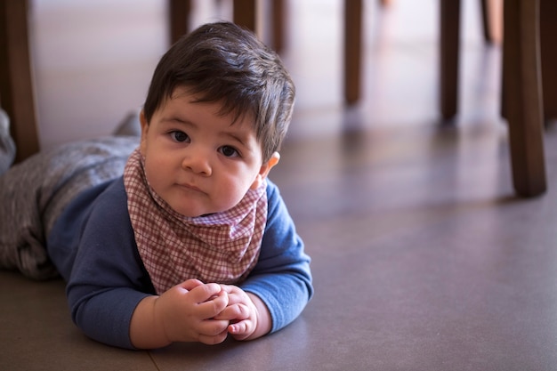 Niño lindo debajo de la mesa mirando a la cámara.