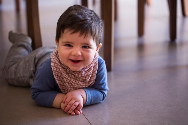 Niño lindo debajo de la mesa mirando a la cámara.