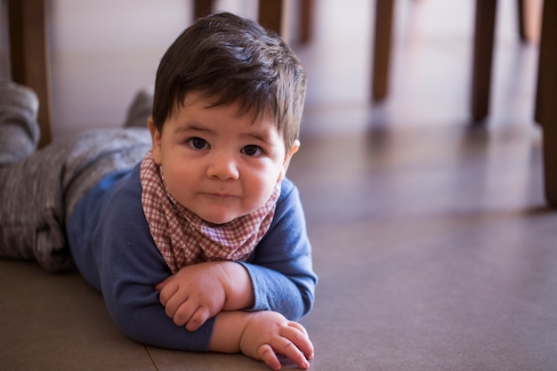 Niño lindo debajo de la mesa mirando a la cámara.