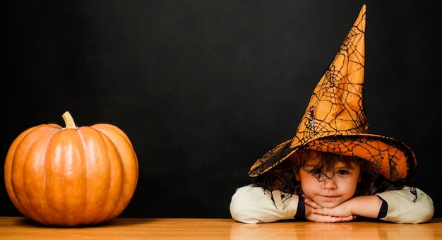 Niño lindo disfrazado de Halloween y sombrero de bruja con calabaza. Vacaciones de otoño de Halloween.