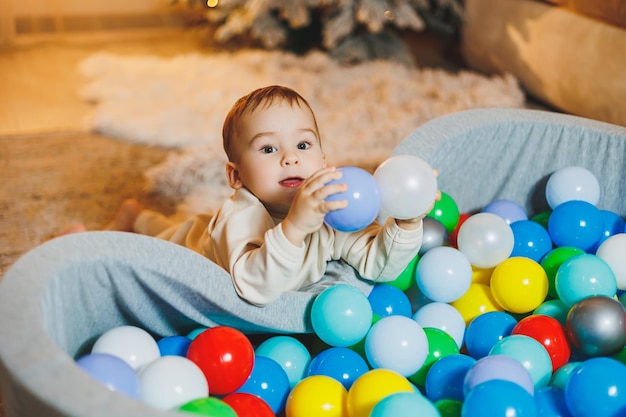 Un niño lindo está jugando en una piscina de bolas de plástico piscina seca para niños en casa