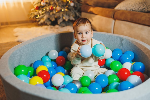 Un niño lindo está jugando en una piscina de bolas de plástico piscina seca para niños en casa