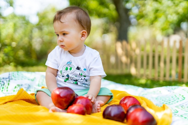 Niño lindo feliz en el jardín Lindo bebé recién nacido sentado con manzanas