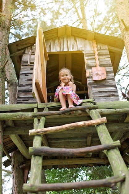 Niño lindo feliz jugando en la casa del árbol