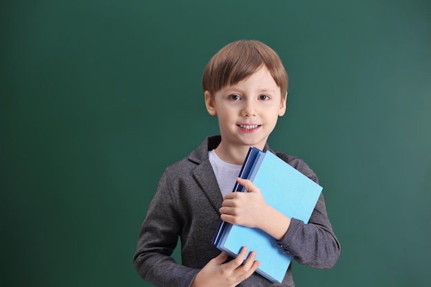 Niño lindo en el fondo de la pizarra de la escuela