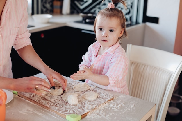 Niño lindo en harina cocinando junto con sus padres en la cocina