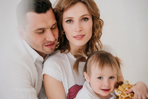 Niño lindo hija y papá cosquillas mamá divirtiéndose bien jugando juntos en casa, padres felices y niña pequeña disfrutando de una actividad divertida y comunicación, familia riendo relajante