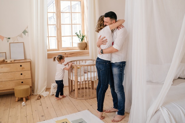 Foto niño lindo hija y papá cosquillas mamá divirtiéndose bien jugando juntos en casa, padres felices y niña pequeña disfrutando de una actividad divertida y comunicación, familia riendo relajante