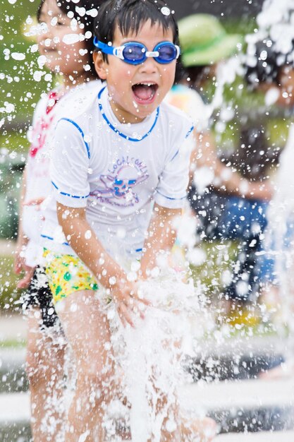 Foto niño lindo jugando en el agua de la fuente