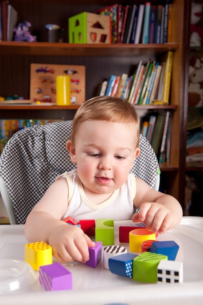 Un niño lindo jugando con bloques de juguete en la mesa.