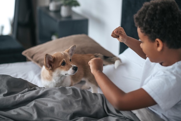 Un niño lindo jugando con un cachorro y sintiéndose emocionado