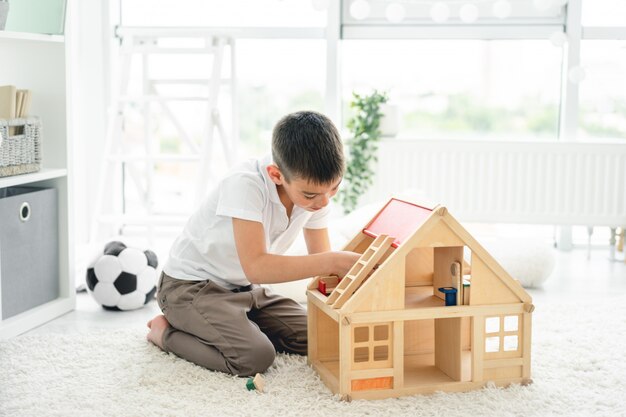 Foto niño lindo jugando con casa de muñecas