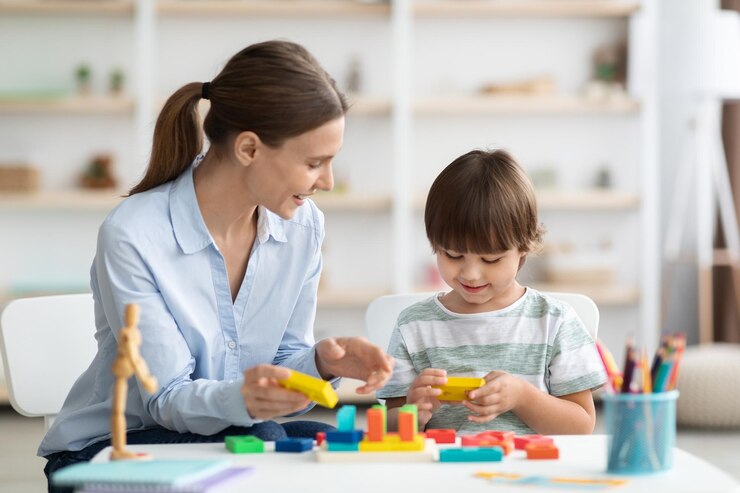 Un niño lindo jugando a un juego lógico con una maestra positiva estudiando juntos en la escuela educativa
