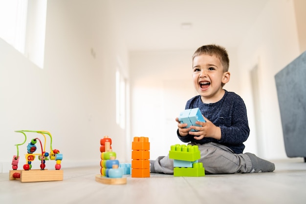 Foto un niño lindo jugando con juguetes en casa.