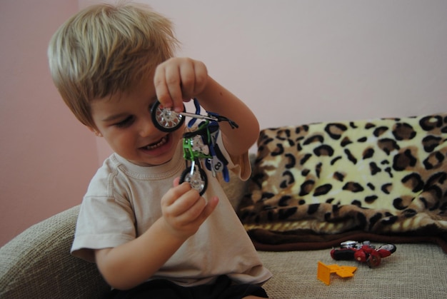 Un niño lindo jugando con juguetes mientras está sentado en el sofá en casa.