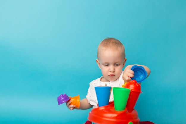 Niño lindo jugando con juguetes de plástico sentados en el suelo Aprendizaje temprano Juguetes en desarrollo