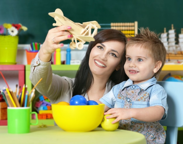 Niño lindo jugando con la madre en casa o jardín de infantes