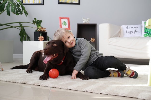 Niño lindo jugando con perro gracioso en casa