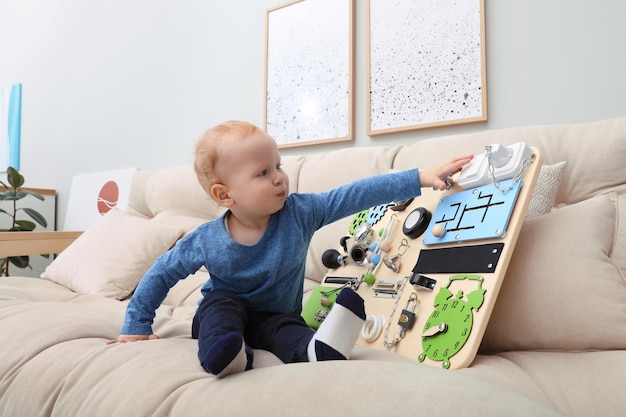 Un niño lindo jugando con una tabla ocupada en el sofá de casa