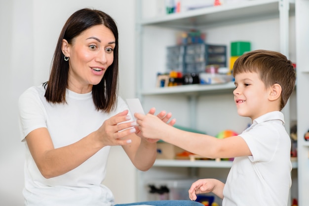 A un niño lindo con un logopeda se le enseña a pronunciar las letras, palabras y sonidos correctamente.