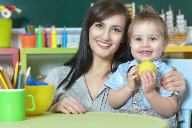 Niño lindo con madre en casa o jardín de infantes