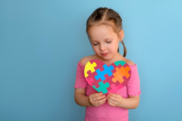 Un niño lindo mira una postal hecha de papel el día de la concientización sobre el autismo