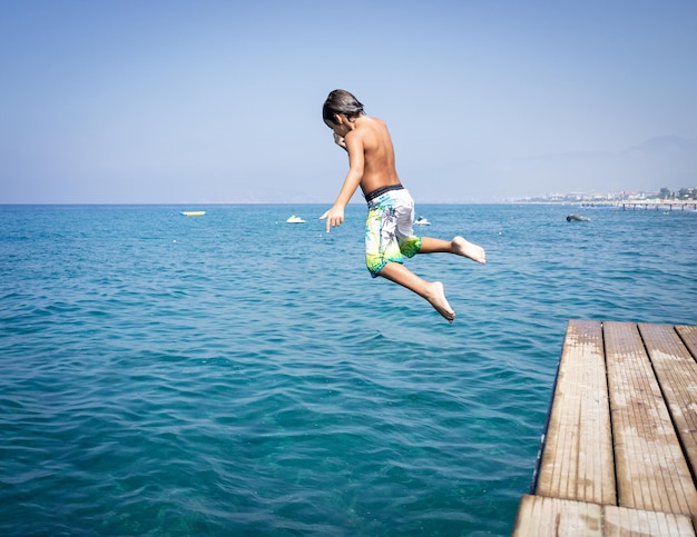 Niño lindo en el muelle del mar disfrutando de las vacaciones