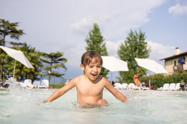 Niño lindo niño chapoteando en la piscina divirtiéndose actividad de ocio