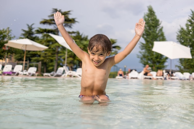 Niño lindo niño chapoteando en la piscina divirtiéndose actividad de ocio