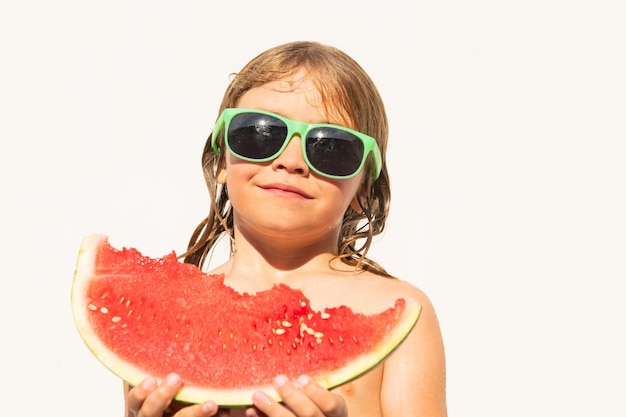 Niño lindo niño en la piscina comiendo sandía. Disfruta comiendo frutas tropicales. Concepto de niños de verano. Infancia feliz.