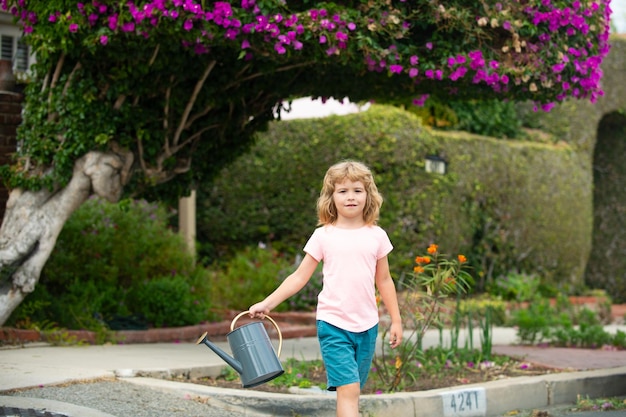 Niño lindo niño regando plantas en el jardín