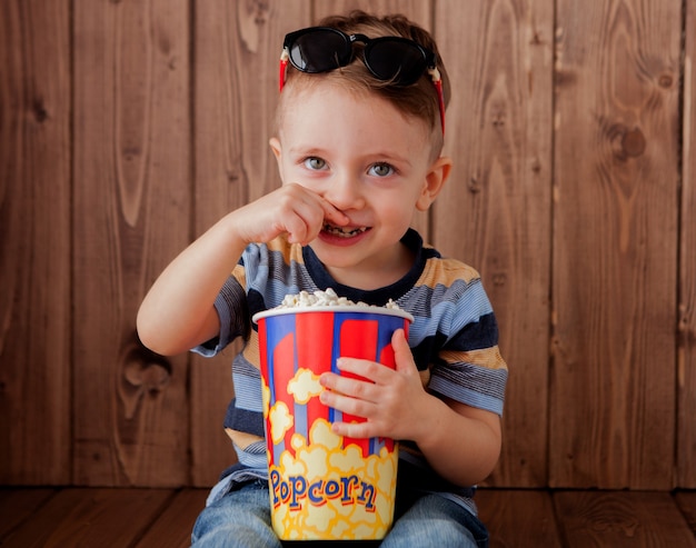 Niño lindo niño sosteniendo un cubo de palomitas de maíz