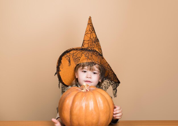 niño lindo de octubre con sombrero de bruja con calabaza de halloween jack o linterna truco o trato calabaza mágica