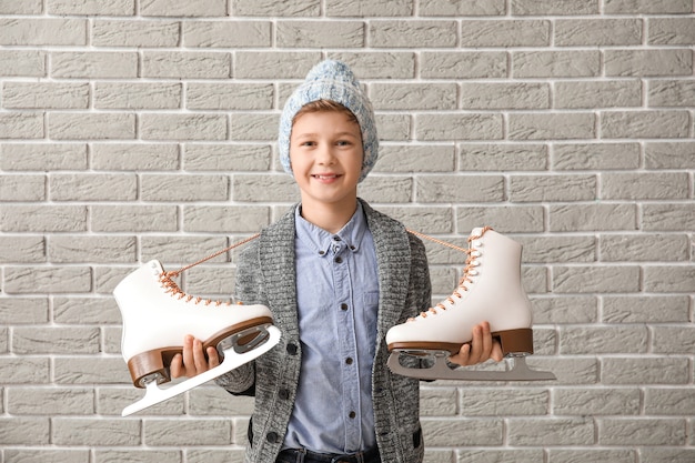 Niño lindo con patines para hielo contra ladrillo