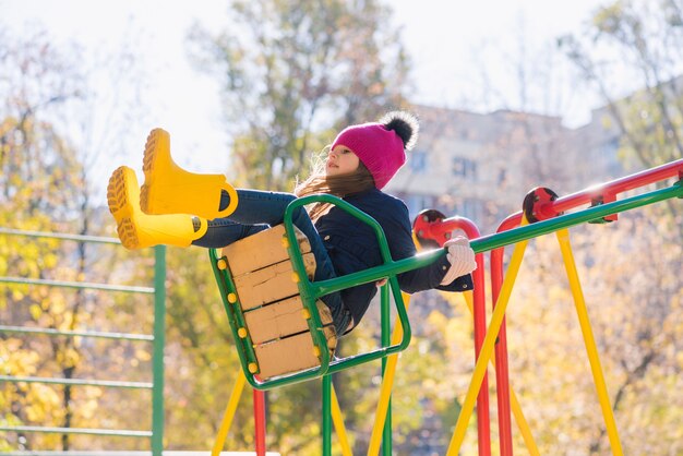 Niño lindo en el patio de recreo durante la caminata de otoño