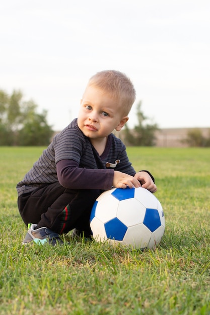 Foto niño lindo con una pelota en el hermoso parque en la naturaleza