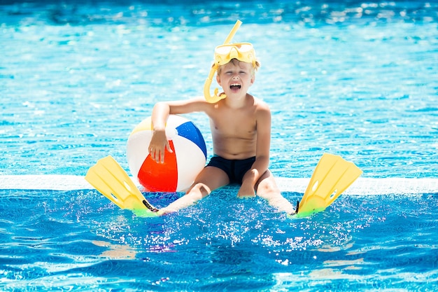 Niño lindo en la piscina. Natación niño divertido.