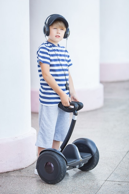 Foto niño lindo que conduce el artilugio eléctrico. niño montando un segway. niño activo al aire libre en verano.