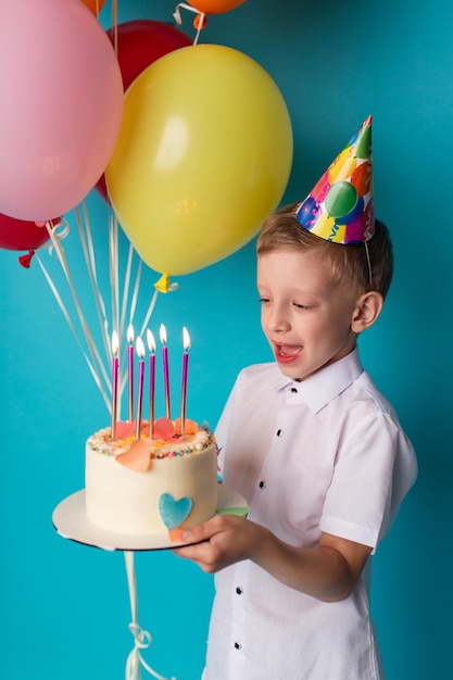 Niño lindo que sopla velas en la fiesta de feliz cumpleaños de la torta