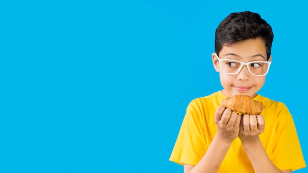 Niño lindo que sostiene un espacio de copia de croissant