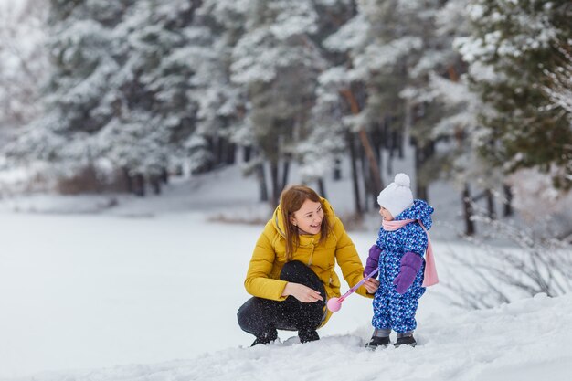 Niño lindo en ropa de abrigo divirtiéndose al aire libre con madre, mamá e hija, vacaciones familiares, ocio