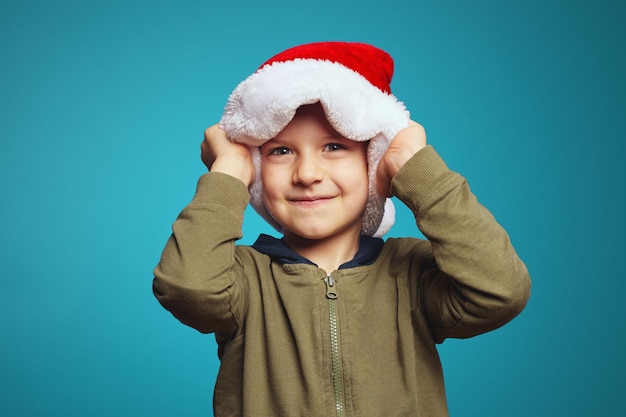 Niño lindo en ropa casual cogidos de la mano en el sombrero de navidad sonriendo