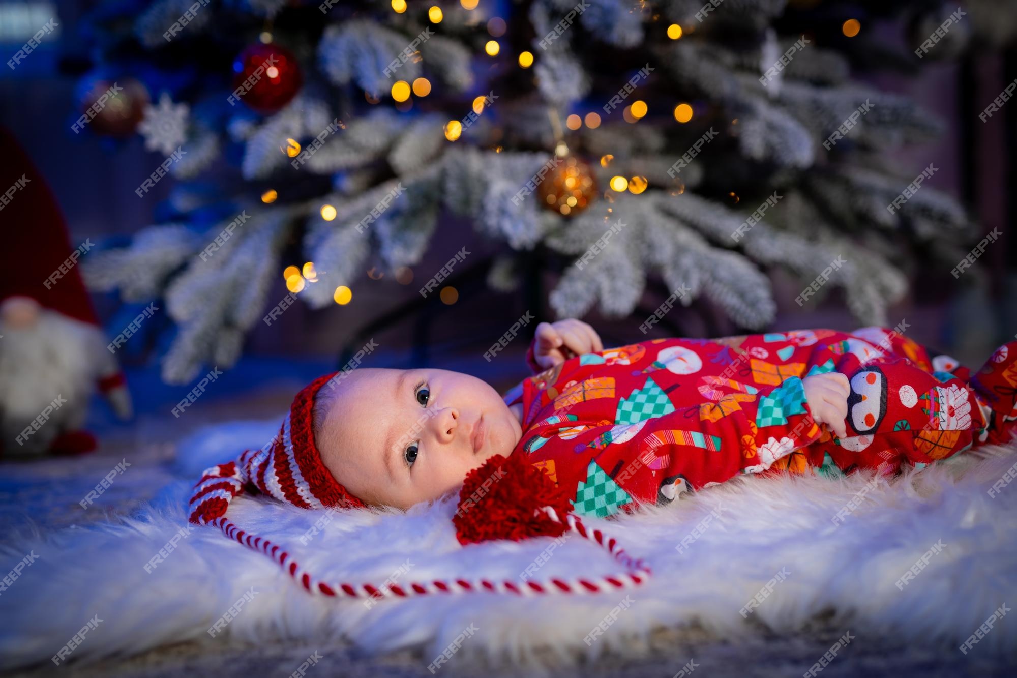 Niño lindo en ropa de navidad bebé acostado en el árbol de pieles el fondo foto de stock Foto Premium
